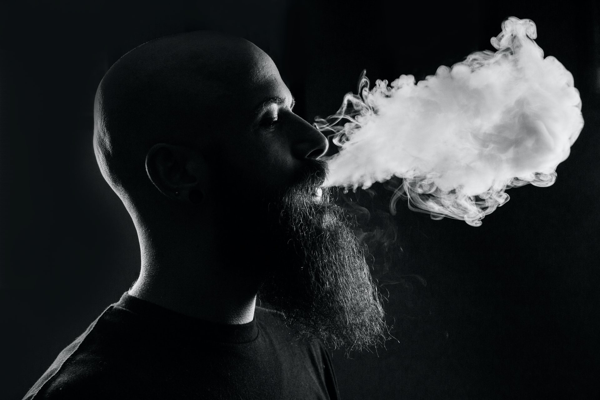 mężczyzna z brodą palący papierosa